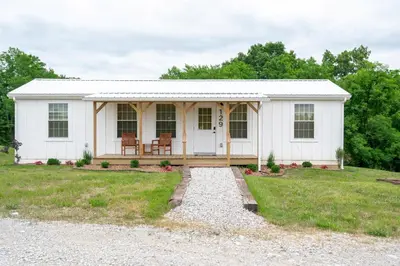 a white tiny house with a porch and a pathway at Block of 4 Lodges at Eden Reserve - For Groups in Williamstown