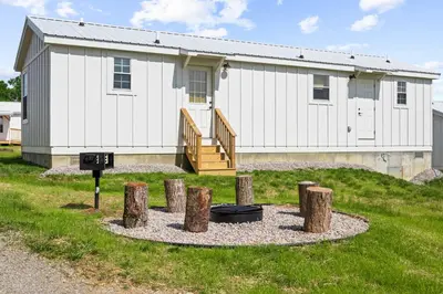 a white building with a fire pit in front of it at The Lodges at Eden Reserve - Cabins Near Ark in Williamstown