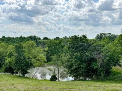 a river in the middle of a field with trees at The Lodges at Eden Reserve - Cabins Near Ark in Williamstown