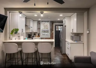 a kitchen with white cabinets and bar stools at 1BR Apt, Minutes to Downtown Cincy, Stadiums, Bars in Ludlow