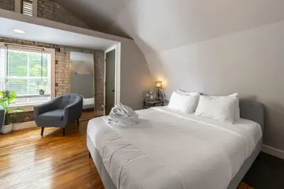 a bedroom with a large white bed and a chair at Close to Stadiums, Downtown Cincy, & more, 1BR Apt in Ludlow