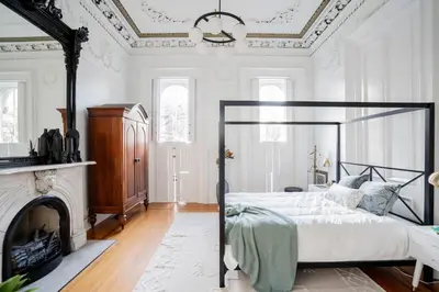 a white bedroom with a bed and a fireplace at Walk to Stadiums & Downtown, Jet Tub, Historic Apt in Covington