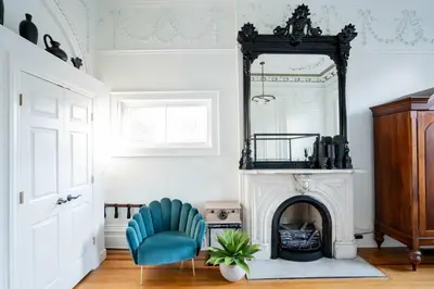 a living room with a mirror and a blue chair at Walk to Stadiums & Downtown, Jet Tub, Historic Apt in Covington