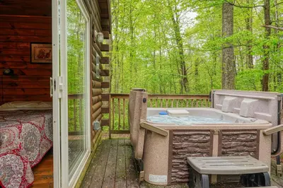 a hot tub on the back porch of a cabin at Blue Rose Cabins - Cupids Cabin in Logan