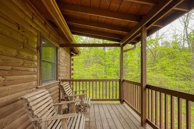 two rocking chairs sitting on the porch of a cabin at Blue Rose Cabins - Lincoln Log Cabin in Logan