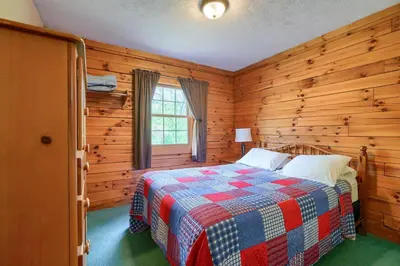 a bedroom with a bed in a log cabin at Blue Rose Cabins - Lincoln Log Cabin in Logan