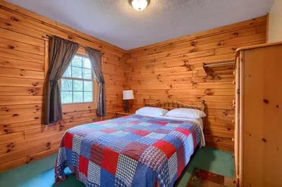 a bedroom with a bed in a wooden room at Blue Rose Cabins - Lincoln Log Cabin in Logan