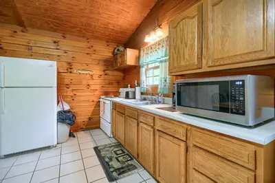 a kitchen with wooden cabinets and a white refrigerator at Blue Rose Cabins - Lincoln Log Cabin in Logan