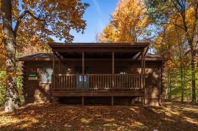 a log cabin with a deck in the woods at Blue Rose Cabins - Lincoln Log Cabin in Logan