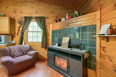 a living room with a fireplace in a log cabin at Blue Rose Cabins - Lincoln Log Cabin in Logan