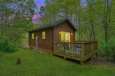 a log cabin with a deck in the grass at Blue Rose Cabins - Lovebirds Cabin in Logan