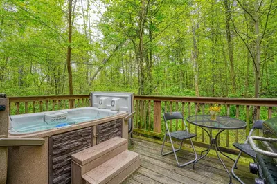 a hot tub on a deck with a table and chairs at Blue Rose Cabins - Lovebirds Cabin in Logan