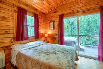 a bedroom with a bed in a log cabin at Blue Rose Cabins - Lovebirds Cabin in Logan