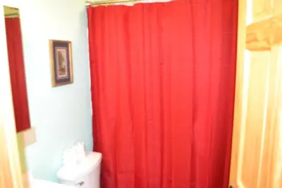 a red shower curtain in a bathroom with a toilet at Blue Rose Cabins - Naughty Pine Cabin in Logan