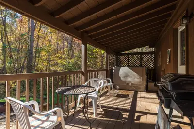 a screened porch with a table and chairs and a tv at Blue Rose Cabins - Naughty Pine Cabin in Logan