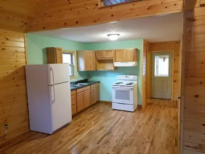 a kitchen with a white refrigerator and wooden cabinets at Blue Rose Cabins - Naughty Pine Cabin in Logan