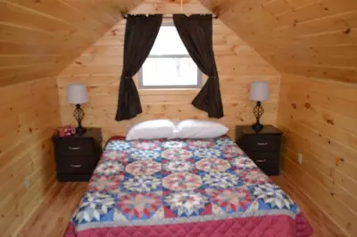 a bedroom with a bed with two night stands and a window at Blue Rose Cabins - Naughty Pine Cabin in Logan