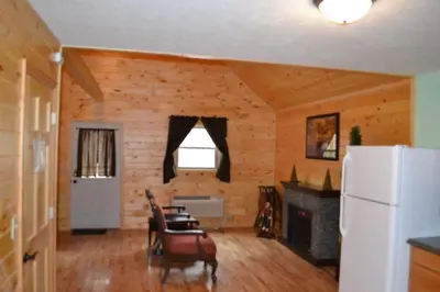 a living room with wooden walls and a refrigerator at Blue Rose Cabins - Naughty Pine Cabin in Logan