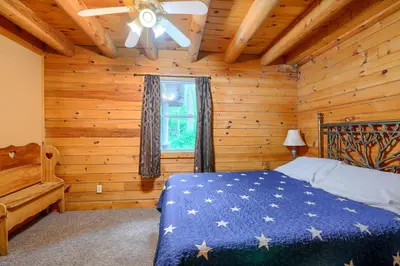 a bedroom with a bed in a log cabin at Blue Rose Cabins - Oleander Cabin in Logan