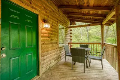 a green door on a porch with a table and chairs at Blue Rose Cabins - Oleander Cabin in Logan