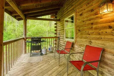 a screened porch with two chairs and a grill at Blue Rose Cabins - Oleander Cabin in Logan