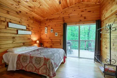a bedroom with a bed in a log cabin at Blue Rose Cabins - Overlook Cabin in Logan