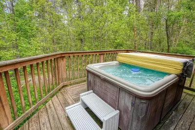 a hot tub on a deck with a bench at Blue Rose Cabins - Overlook Cabin in Logan