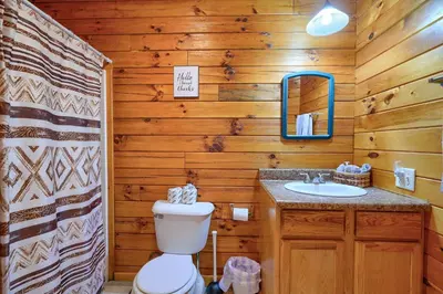 a bathroom with a toilet and a sink and a mirror at Blue Rose Cabins - Overlook Cabin in Logan