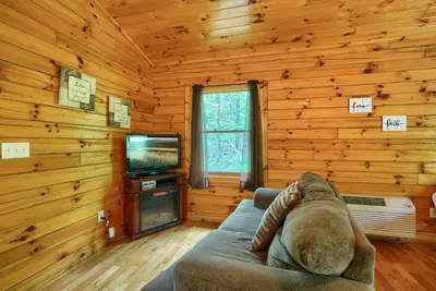 a living room with a couch and a television at Blue Rose Cabins - Overlook Cabin in Logan