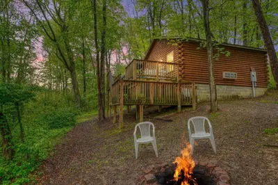 two chairs and a fire in front of a log cabin at Blue Rose Cabins - Pine Ridge Cabin in Logan