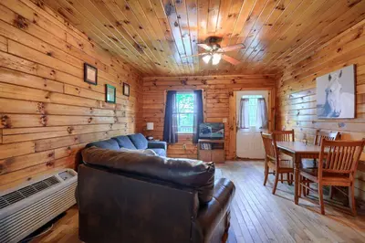 a living room with a couch and a dining room at Blue Rose Cabins - Pine Ridge Cabin in Logan