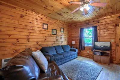 a living room with a leather couch and a television at Blue Rose Cabins - Pine Ridge Cabin in Logan