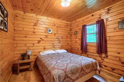 a bedroom with a bed in a log cabin at Blue Rose Cabins - Pine Ridge Cabin in Logan