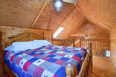 a bedroom with a bed in a wooden room at Blue Rose Cabins - Pinecrest Cabin in Logan