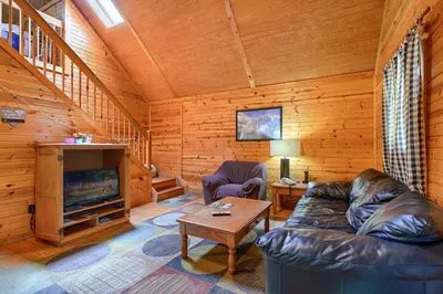 a living room with a leather couch and a fireplace at Blue Rose Cabins - Pinecrest Cabin in Logan