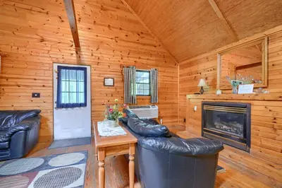 a living room with leather furniture and a fireplace at Blue Rose Cabins - Pinecrest Cabin in Logan