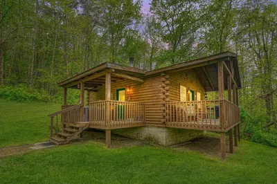 a log cabin with two decks in the grass at Blue Rose Cabins - Rosebud Cabin in Logan