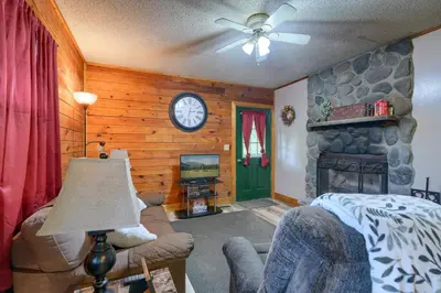 a living room with a fireplace and a clock on the wall at Blue Rose Cabins - Rosebud Cabin in Logan