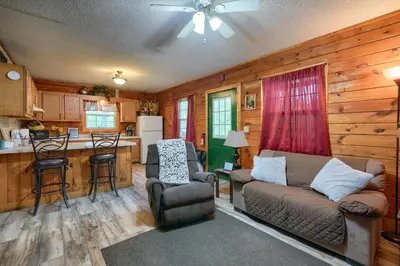a living room with a couch and a kitchen at Blue Rose Cabins - Rosebud Cabin in Logan