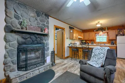 a living room with a stone fireplace next to a kitchen at Blue Rose Cabins - Rosebud Cabin in Logan