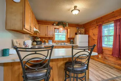 a kitchen with two bar stools in a cabin at Blue Rose Cabins - Rosebud Cabin in Logan