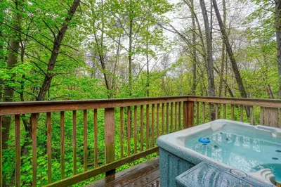 a hot tub on a wooden deck with trees at Blue Rose Cabins - Treetops Cabin in Logan