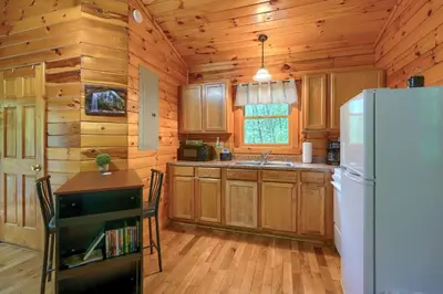 a kitchen with wooden cabinets and a refrigerator at Blue Rose Cabins - Treetops Cabin in Logan