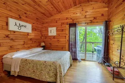 a bedroom with a bed in a log cabin at Blue Rose Cabins - Treetops Cabin in Logan