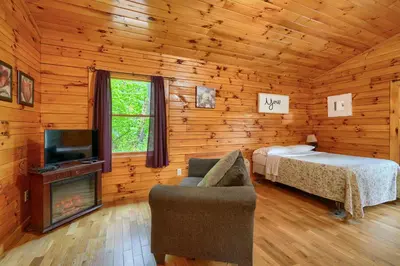 a bedroom with a bed and a television in a log cabin at Blue Rose Cabins - Treetops Cabin in Logan