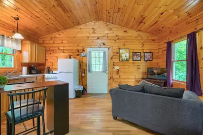 a living room with a couch and a kitchen at Blue Rose Cabins - Treetops Cabin in Logan