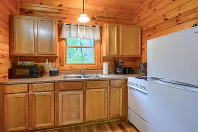 a kitchen with wooden cabinets and a white refrigerator at Blue Rose Cabins - Wildwoods Cabin in Logan