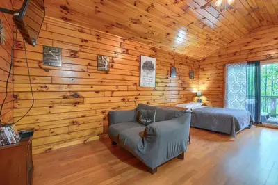 a log cabin with a couch and a bed at Blue Rose Cabins - Wildwoods Cabin in Logan