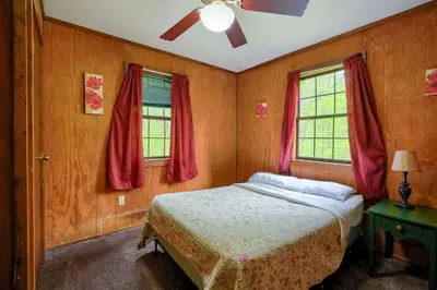 a bedroom with a bed and two windows at Blue Rose Cabins - Rosewood Cabin in Logan