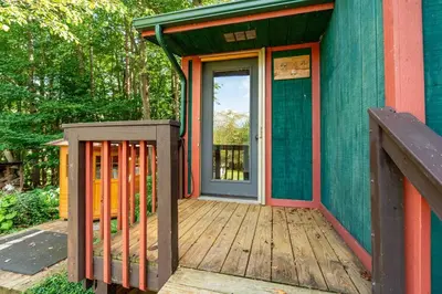 a front door of a house with a wooden deck at Beautiful Tiny House, Sauna, Mohican Getaway in Perrysville